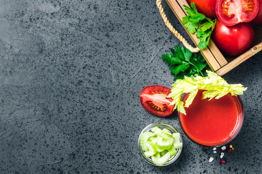 Celery tomato juice in glasses on dark concrete background. Top view, space for text.