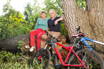 Plakat happy senior couple ride on bicycle in the park