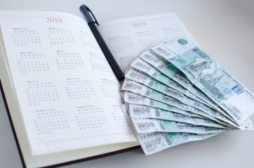 Opened diary, pen and banknotes on white background