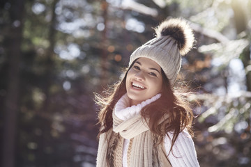 Portrait of laughing young woman wearing knitwear in winter forest