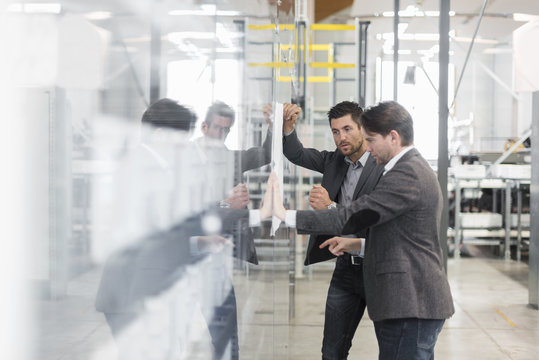 Two businessmen looking at plan in modern factory