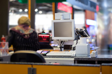 Rows of cash desks with cashiers and customers on blurry background