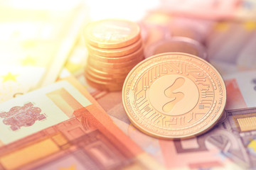 shiny golden SHOPEO cryptocurrency coin on blurry background with euro money