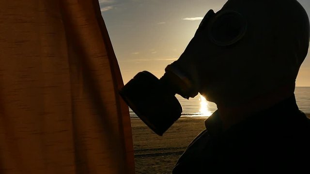 man in gas mask closing a curtain with nice sunny day and beautiful landscape view