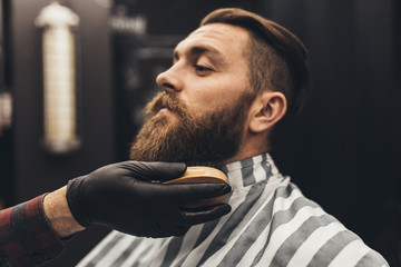 Fototapeta Hipster young good looking man visiting barber shop. Trendy and stylish beard styling and cut. obraz