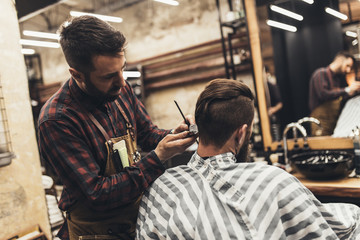 Hipster young good looking man visiting hairstylist in barber shop.