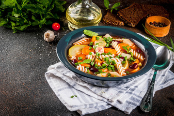 Italian vegetable soup Minestrone with fusilli pasta,  vegetarian food concept, dark rusty background, copy space