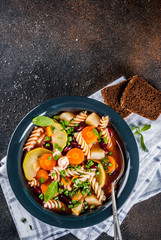 Italian vegetable soup Minestrone with fusilli pasta,  vegetarian food concept, dark rusty background, copy space