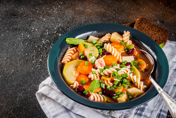 Italian vegetable soup Minestrone with fusilli pasta,  vegetarian food concept, dark rusty background, copy space