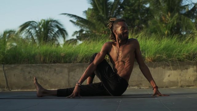 Man practice spine twisting yoga pose at rooftop at sunrise rapid slow motion