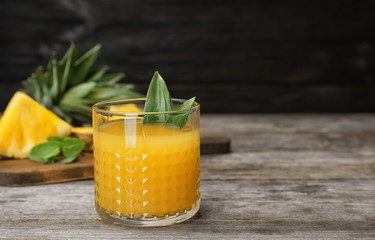 Glass with delicious pineapple juice on table