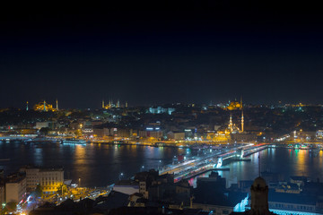 Fototapeta na wymiar Long exposure cityscape of Istanbul at a night. Galata bridge on Golden Horn gulf. Wonderful romantic old town at Sea of Marmara. Bright light of street lighting and various ships. Istanbul. Turkey.