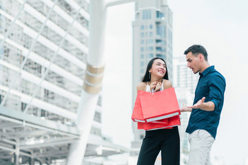 Happy couple with shopping bags at outdoors. Wife makes her husband surprised with the purchase. concept of business shopping, buyer, consumer and attractive lover.