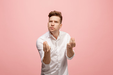 Beautiful male half-length portrait isolated on pink studio backgroud. The young emotional surprised man