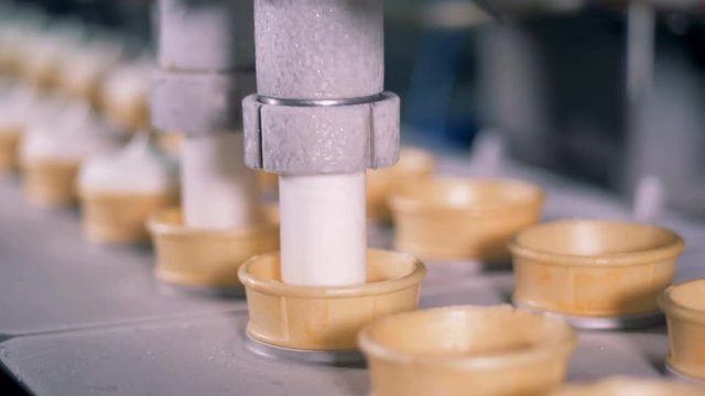 Fast motion process of filling wafer cups with ice-cream in a factory