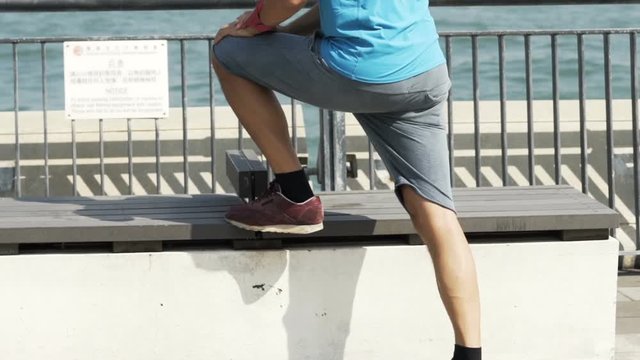 Young man, jogger stretching by river in city, super slow motion
