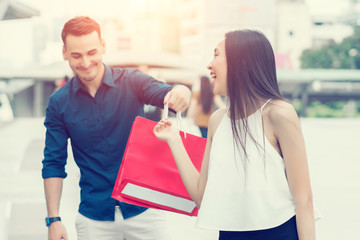 Happy couple with shopping bags at outdoors. Wife makes her husband surprised with the purchase. concept of business shopping, buyer, consumer and attractive lover.