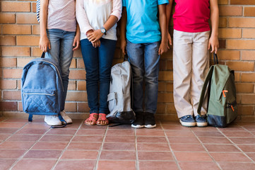 Children legs with backpacks at school