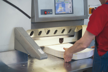 Hands of worker in typography working on cutter guillotine machine