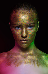 beautiful girl face, painted with gold paint with glitter. particles of a volatile powder. metallic.