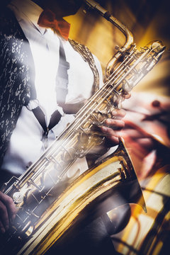 The saxophonist expressively plays the gold saxophone at a concert in the city park.