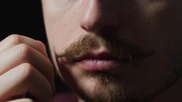 Close up of a man touching his mustache