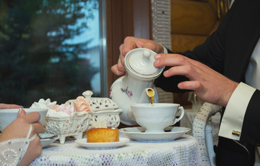 The bridegroom pours tea from the kettle into a cup