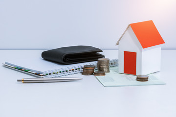 saving account passbook or financial statement, paper house model, and coins on office desk table.