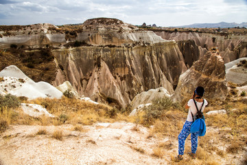 Young woman with camera and backpack taking picture at Cappadocia, Turkey.