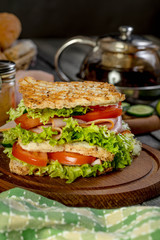 Sandwich with ham, cucumber, tomato and lettuce.