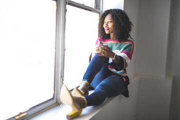 Black woman sit on the side of window