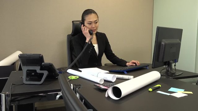 Busy Asian people at work in executive office. Beautiful Japanese business woman working with computer in corporate studio. Confident businesswoman and female manager talking on the phone