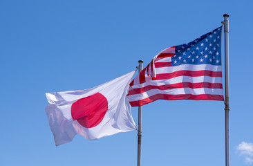 Fototapeta premium American and Japanese Flags waving against blue Sky