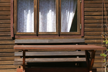 Fototapeta na wymiar Wooden table in front of garden house with window. Empty table near summerhouse.