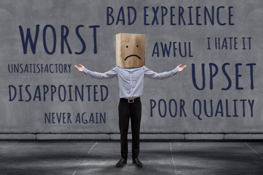 Customer Experience Concept, Unhappy Businessman Client with Sadness Emotion Face on Paper Bag, Blurred Concrete Wall with Wording of Negative Reviews as background