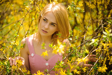 Young girl standing between branches of yellow blossom tree