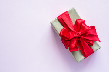 Gift box with red ribbon, a bouquet of tulips on a soft pink pastel background