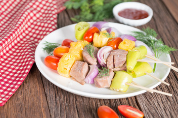 Bbq meat on sticks, kebab skewers with sauce, on wooden background. Traditional barbecue grill food.