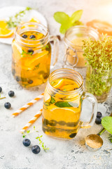 Orange Blueberry Detox Water or lemonade with mint in glass jar on ligth table