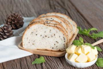 Sliced of sesame bread with butter on wood background.
