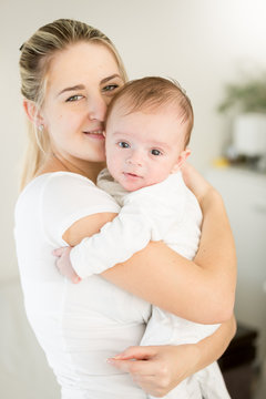 Portrait of smiling young mother hugging her 3 months old baby boy