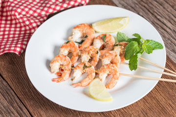 Grilled shrimp skewers served on plate.
