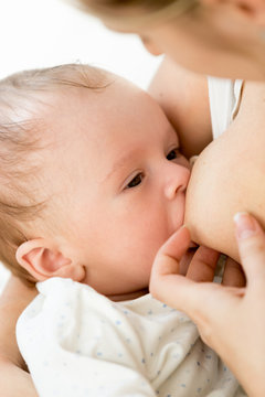 Closeup portrait of 3 months old baby boy eating milk from mothers breast