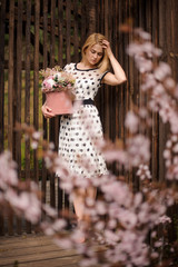 Young girl standing near the fence with a box of flowers
