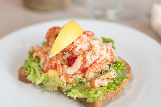 Sandwich with shrimp and lemon on plate.