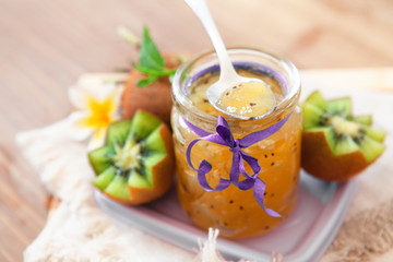 Exotic kiwi jam with ripe fruits on wooden background