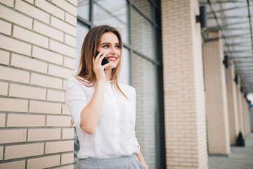 Happy woman on the phone in the city. Smiling woman talking on mobile phone in front of building.