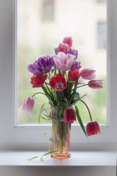 bouquet di grandi tulipani multicolori su una finestra bianca in un vaso di vetro