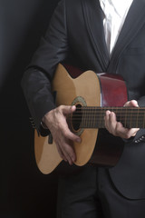 Fototapeta na wymiar Man in black suit with acoustic classic guitar