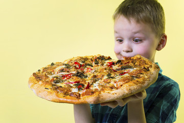 funny boy eating a big pizza on a bright yellow background